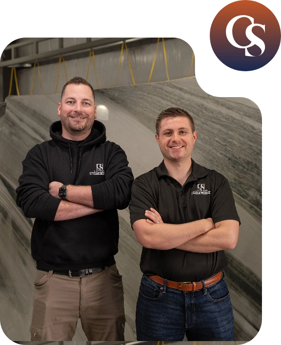 Two team members standing side by side in a room, representing part of a larger group, with casual attire and neutral background.