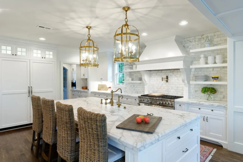 “Spacious kitchen featuring white cabinetry, marble island with drawers, and warm wood flooring.”